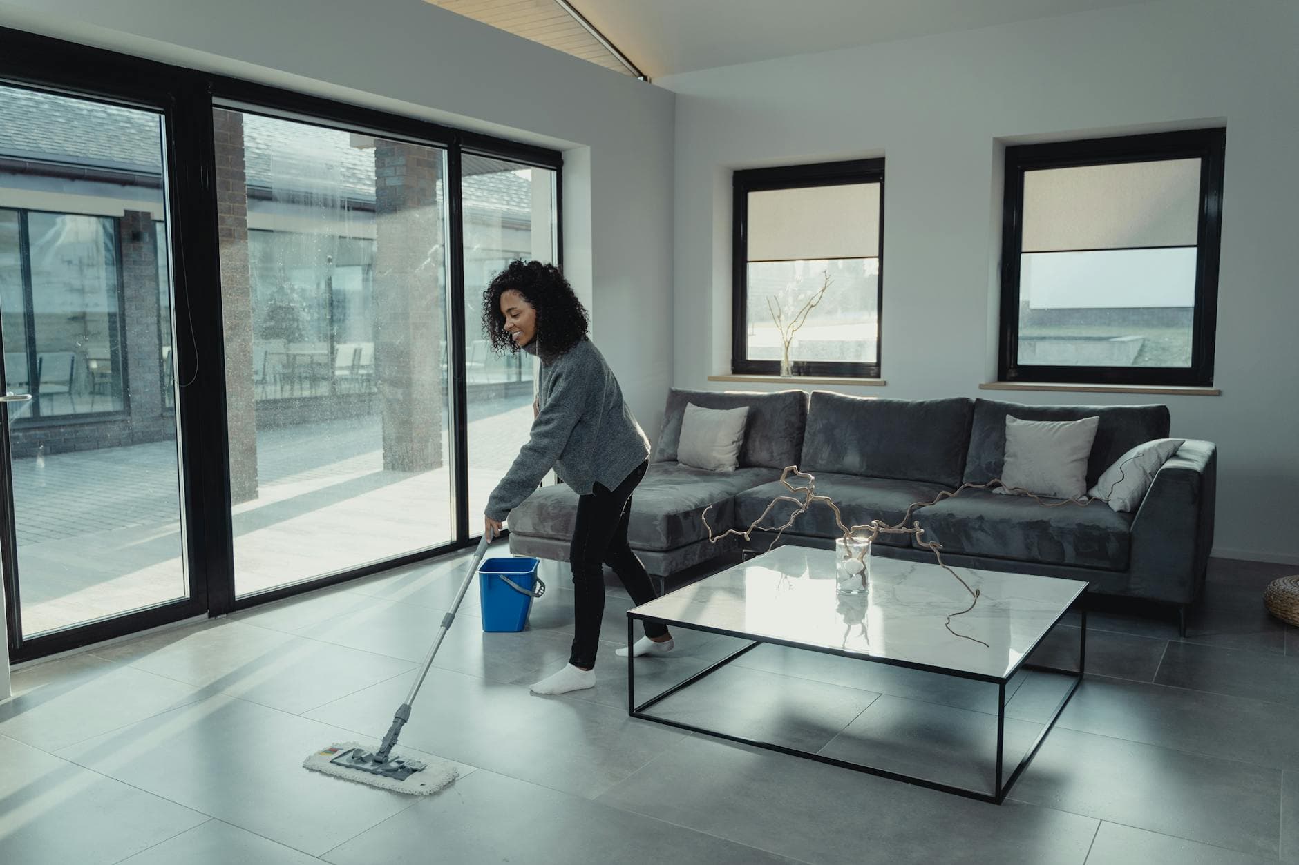 House cleaner mopping a bright, modern Long Island apartment with large windows — cleaning services in Manhasset, Nassau County