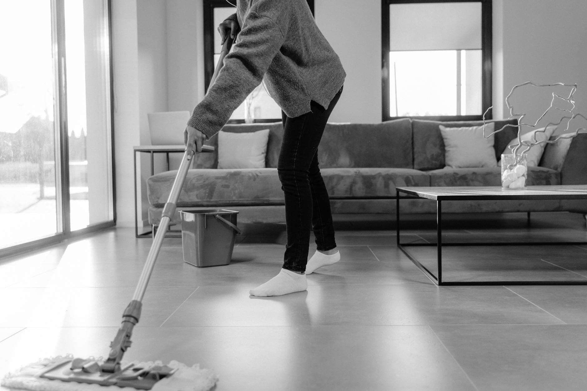 Professional Long Island cleaner mopping the floor in a modern apartment living room — Weekly Maid Service in Port Washington, Nassau County