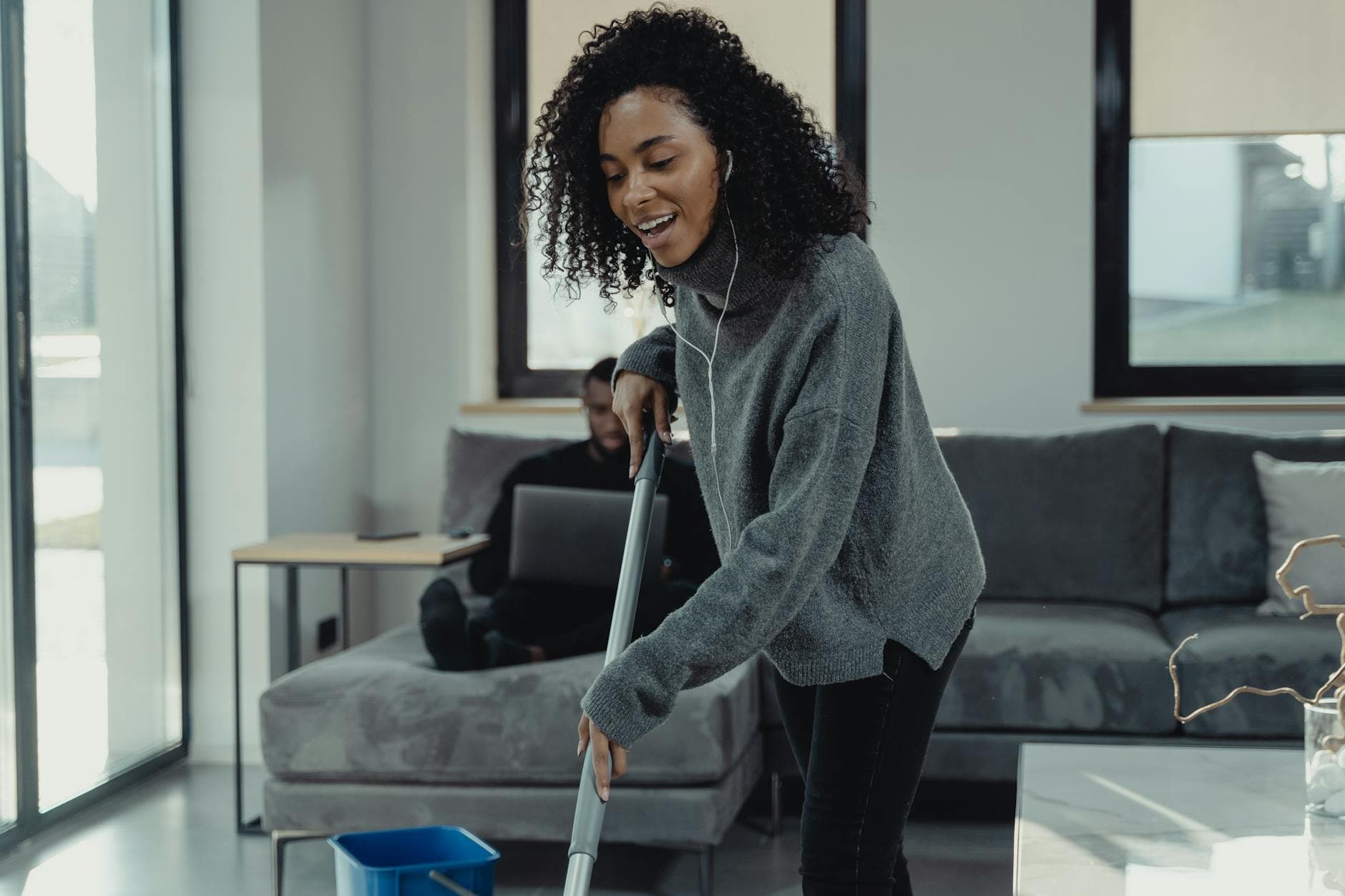 A professional house cleaner mopping the floor of a cozy Long Island living room — Weekly Maid Service in Long Island