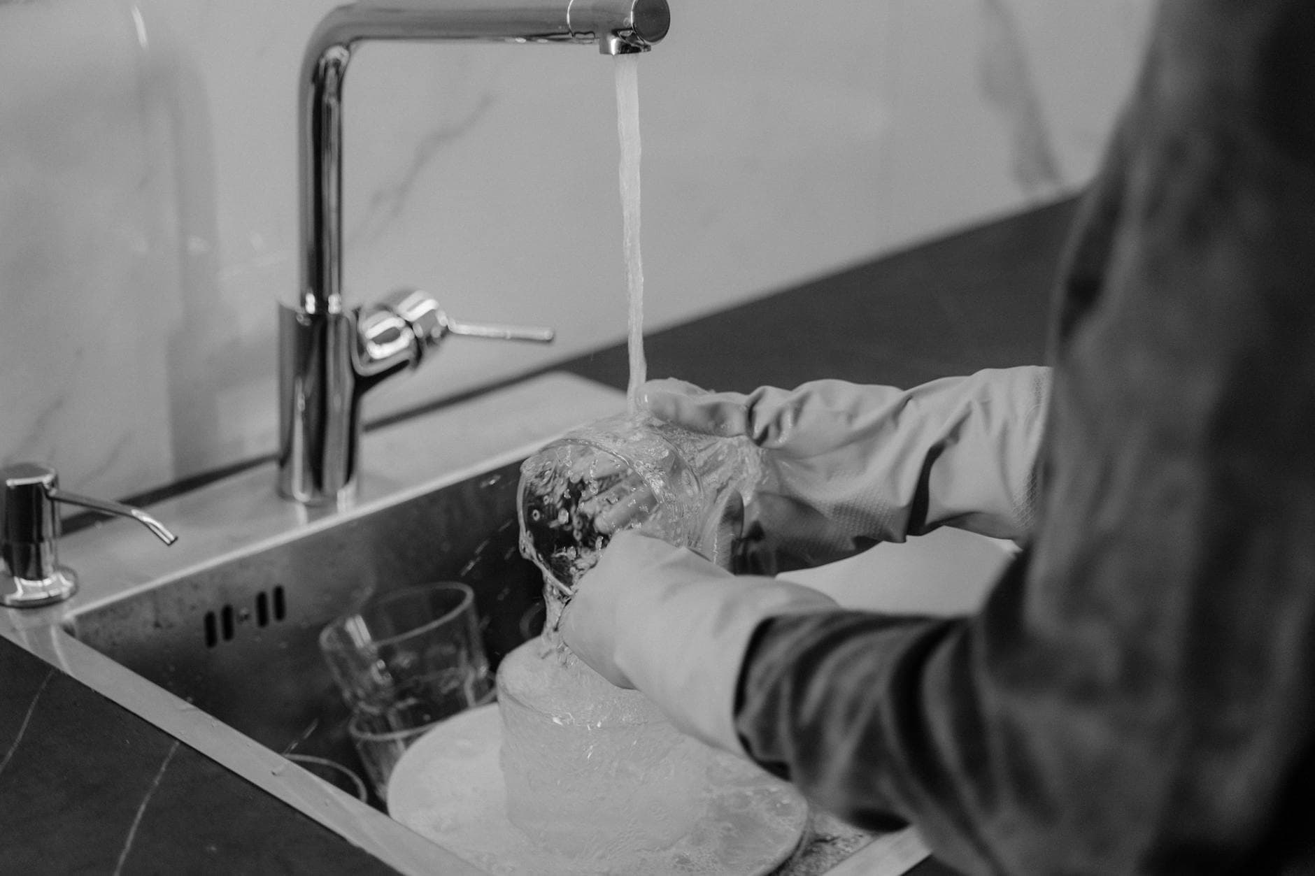 Long Island kitchen cleaning service washing dishes under running water at the sink — cleaning services in Port Washington, Nassau County